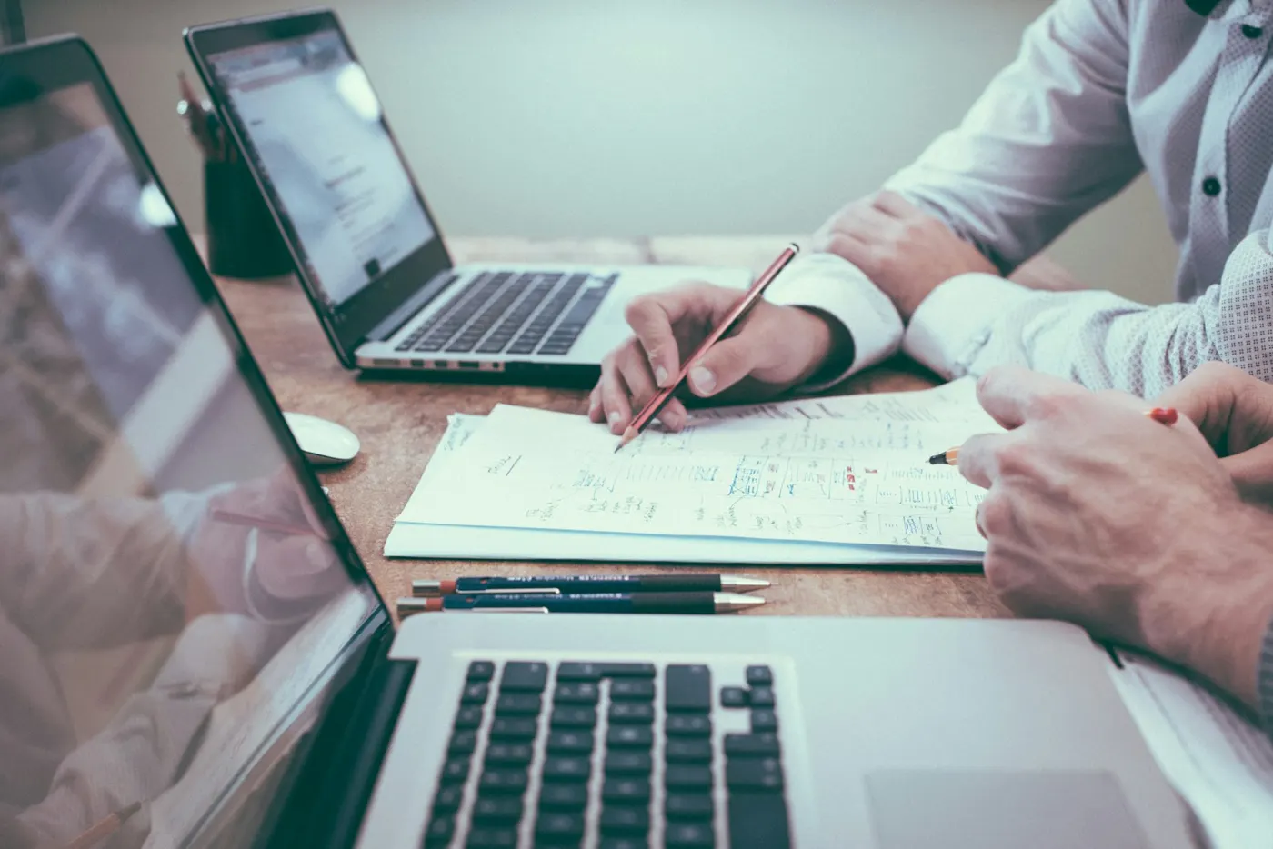 Manos trabajando en un plan de marketing junto a dos laptops